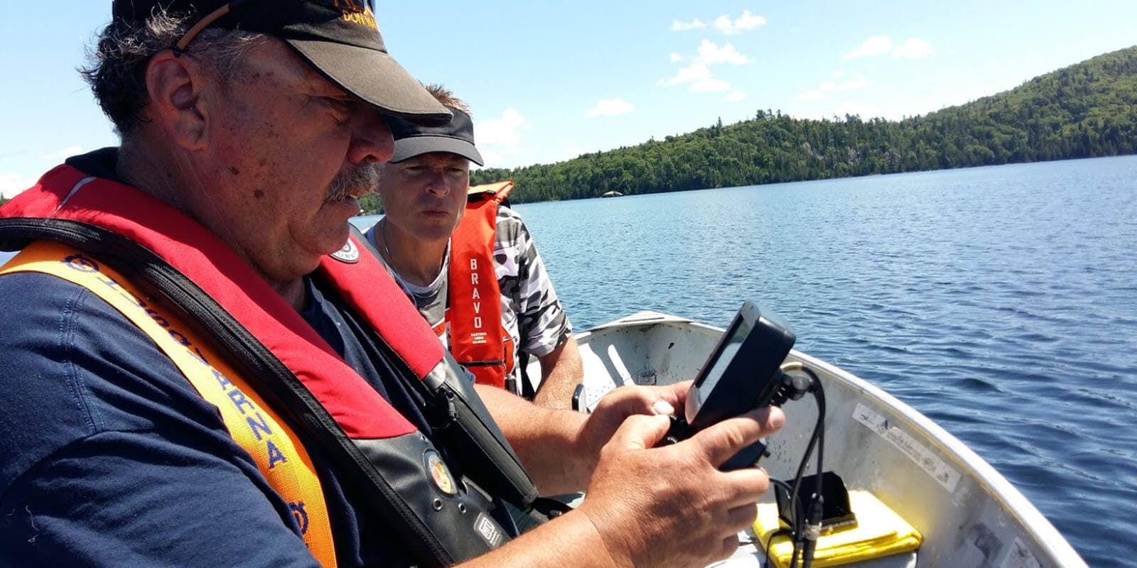 2 men on a boat looking at the screen of a Deep Trekker controller 