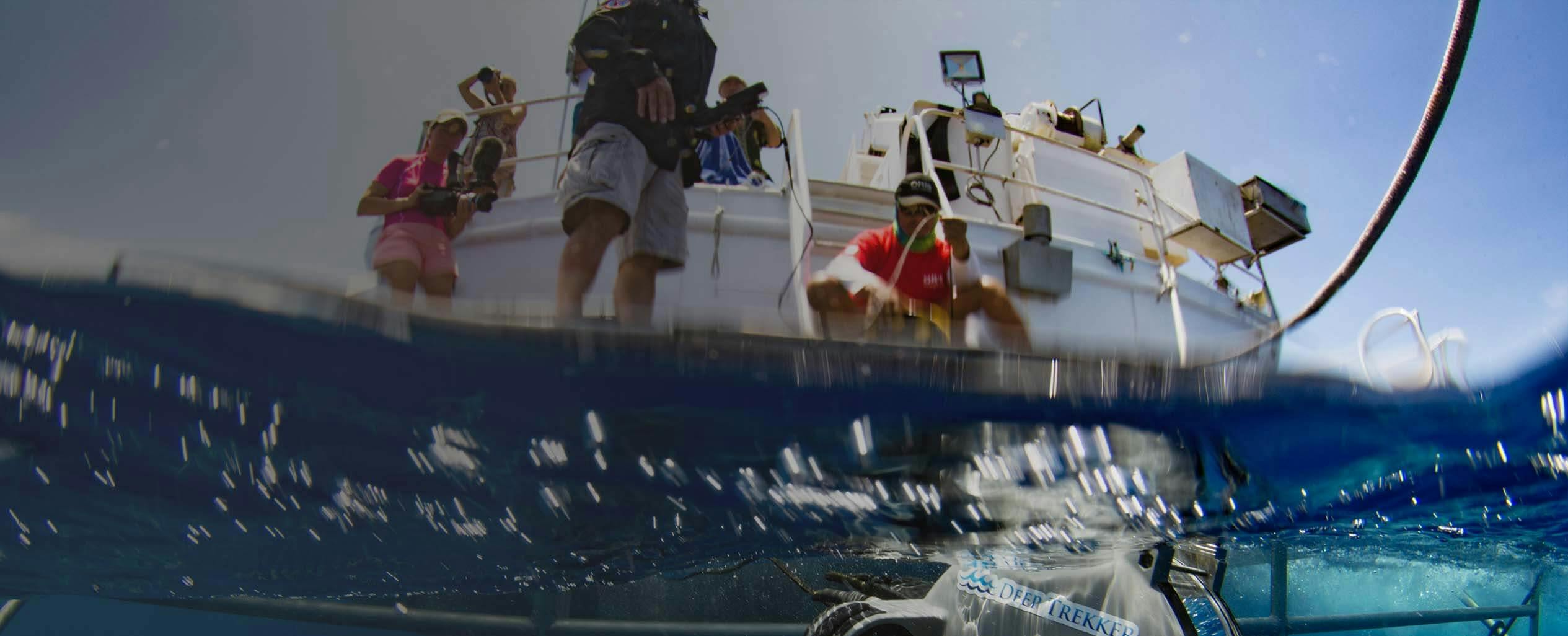 Underwater view of 3 people on white boat throwing a Deep Trekker DTG3 ROV underwater