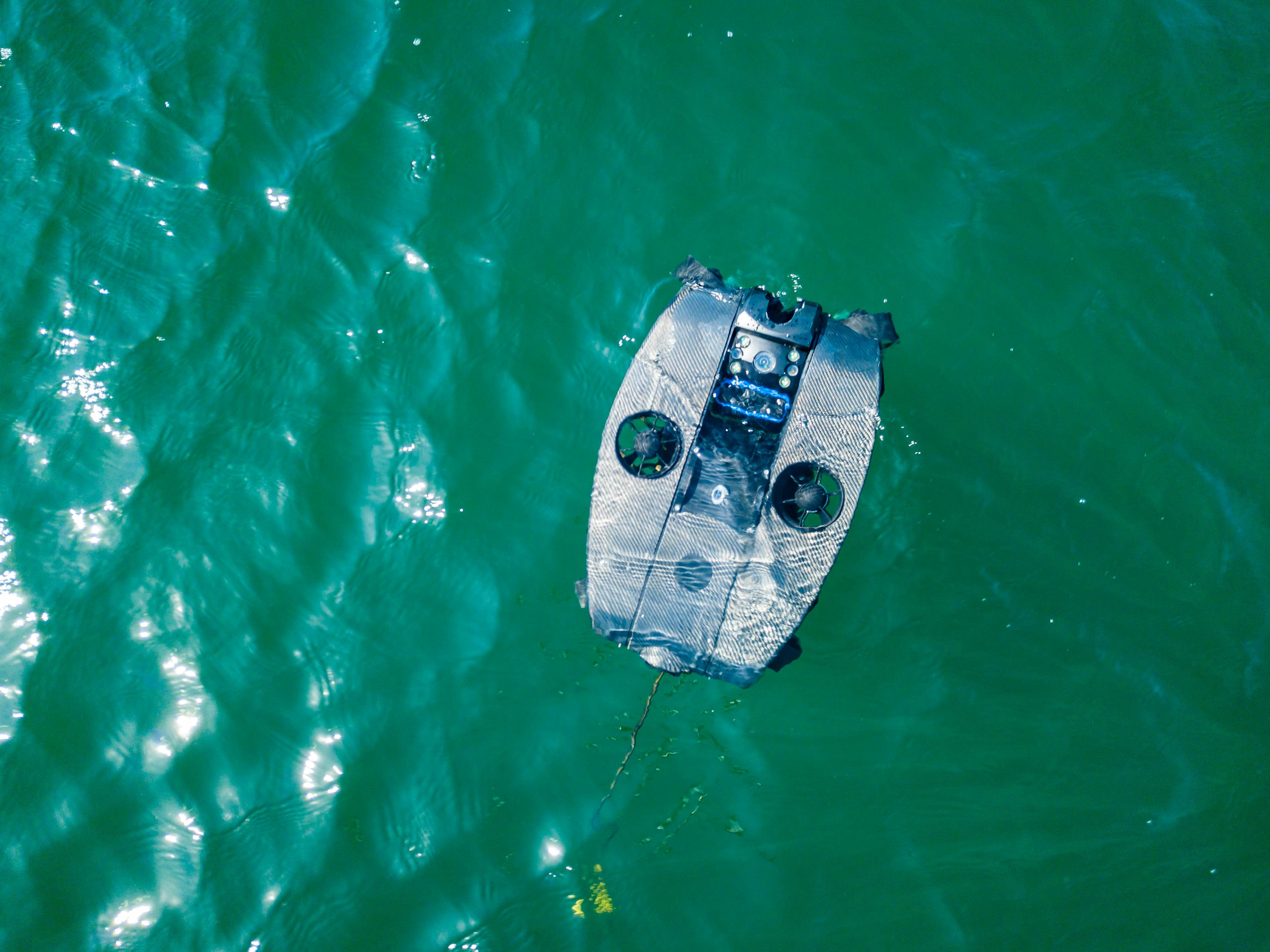 Aerial shot of a Deep Trekker REVOLUTION ROV swimming in blue green water