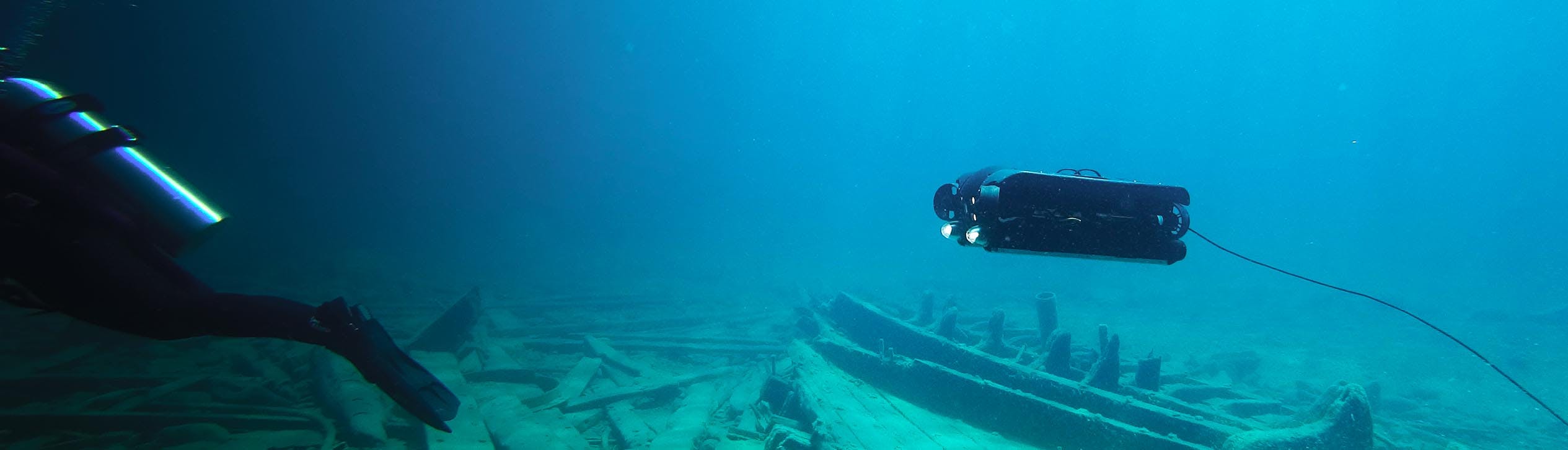 Deep Trekker REVOLUTION ROV swimming underwater over shipwreck following scuba diver