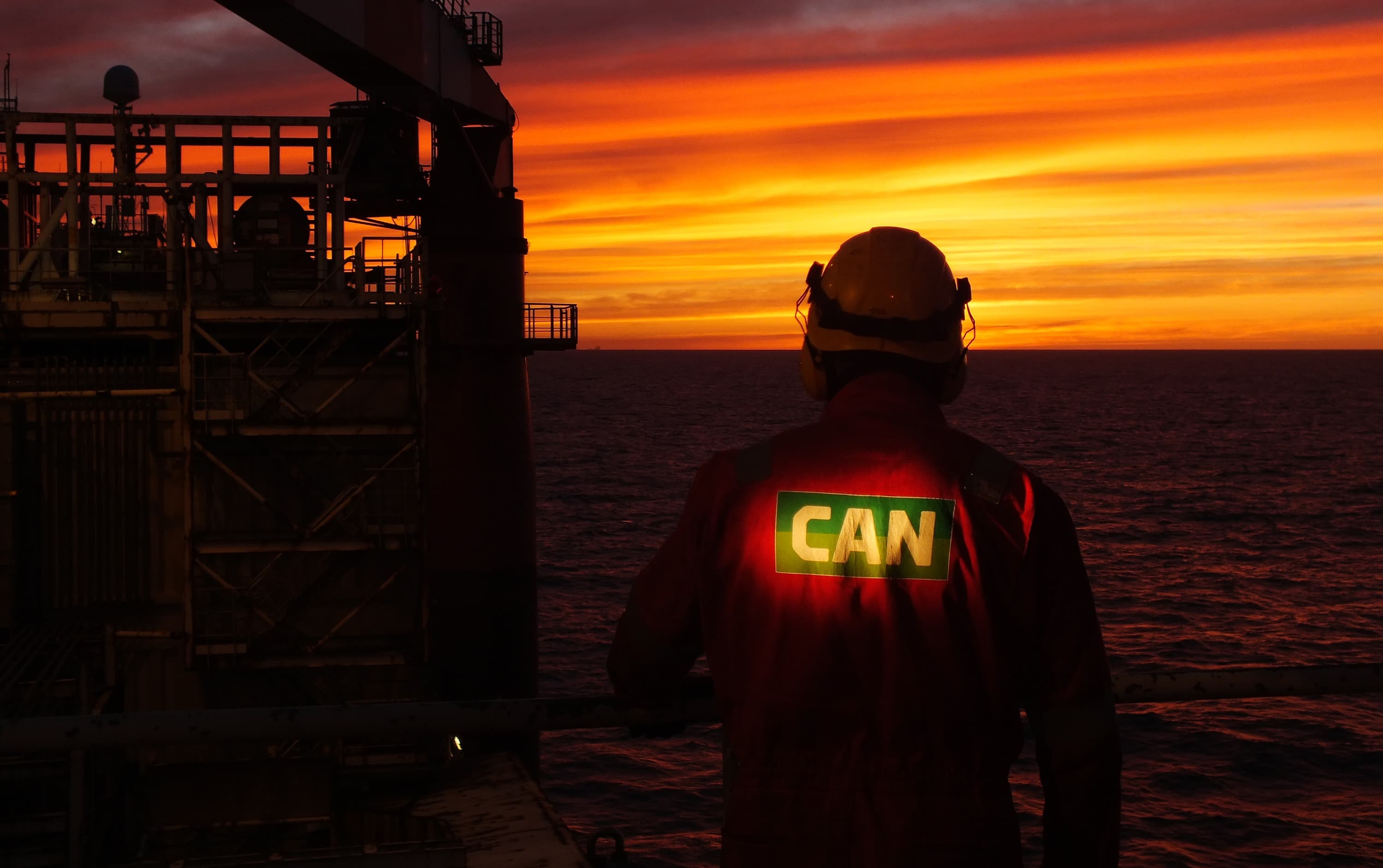 silhouette of an operator standing on deck of fpso during a sunset for underwater rov ballast tank inspection