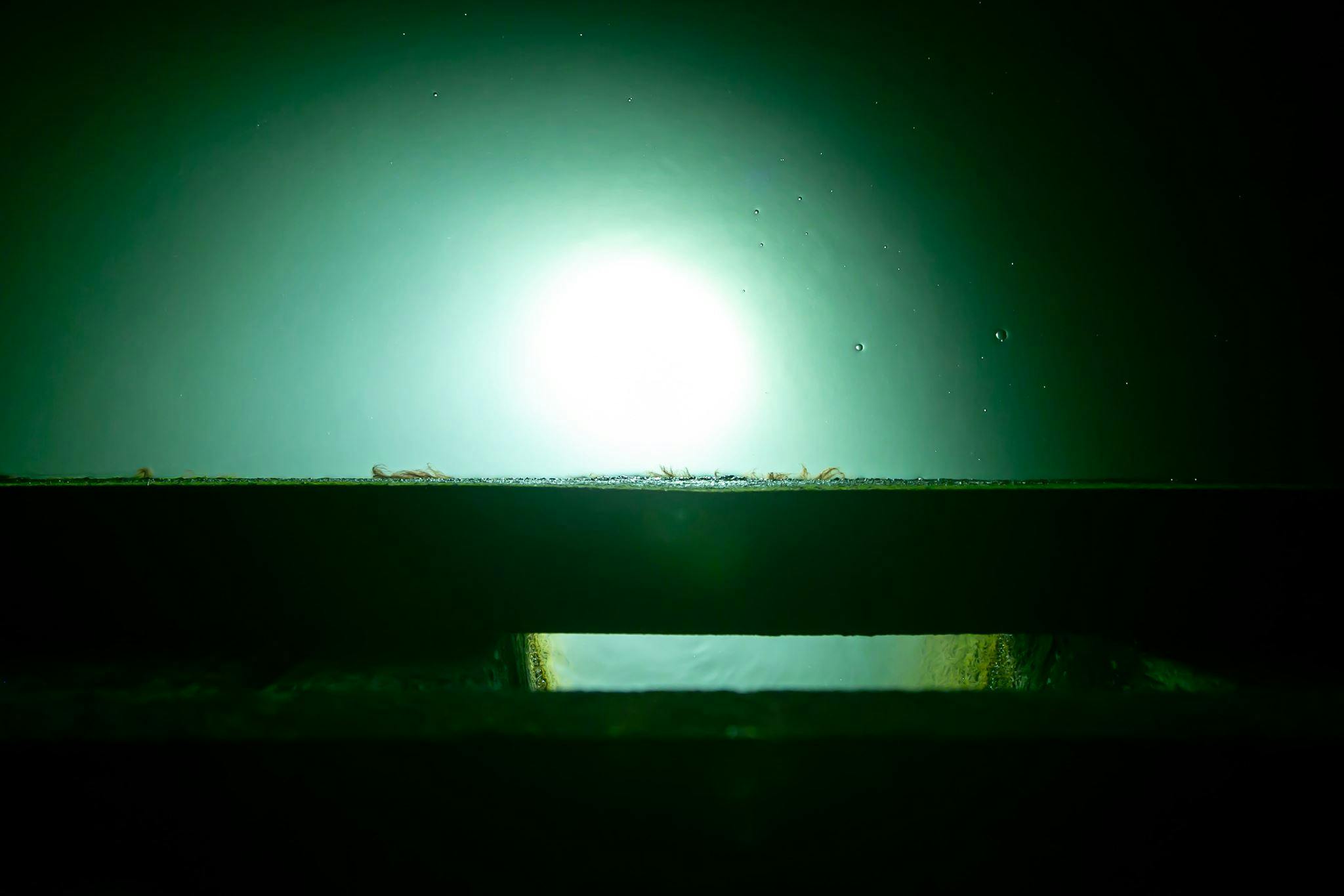 Deep Trekker ROV light coming up through dark water 