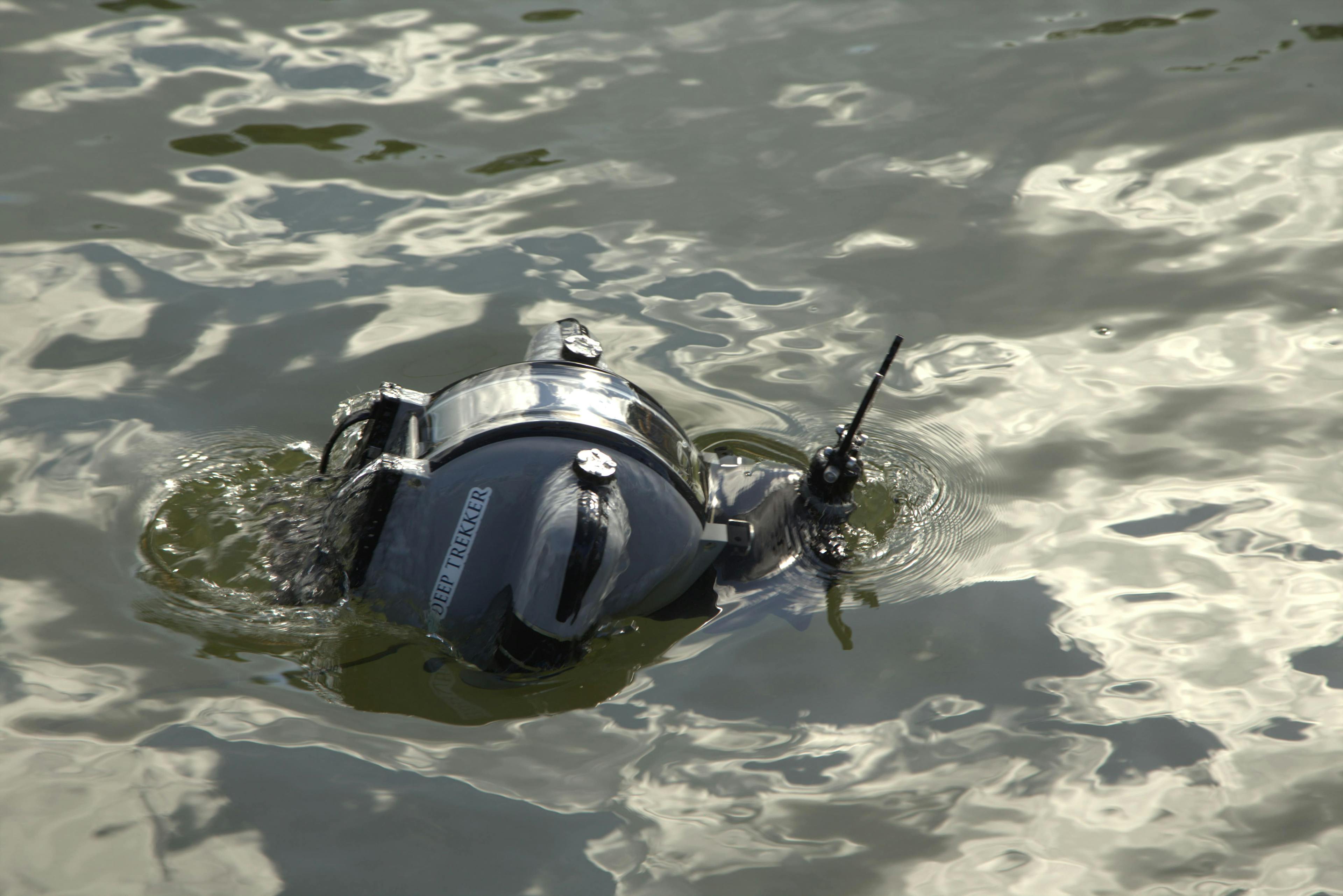 The Deep Trekker DTG3 underwater ROV surfacing out of grey water with the grabber arm coming out of the water first 