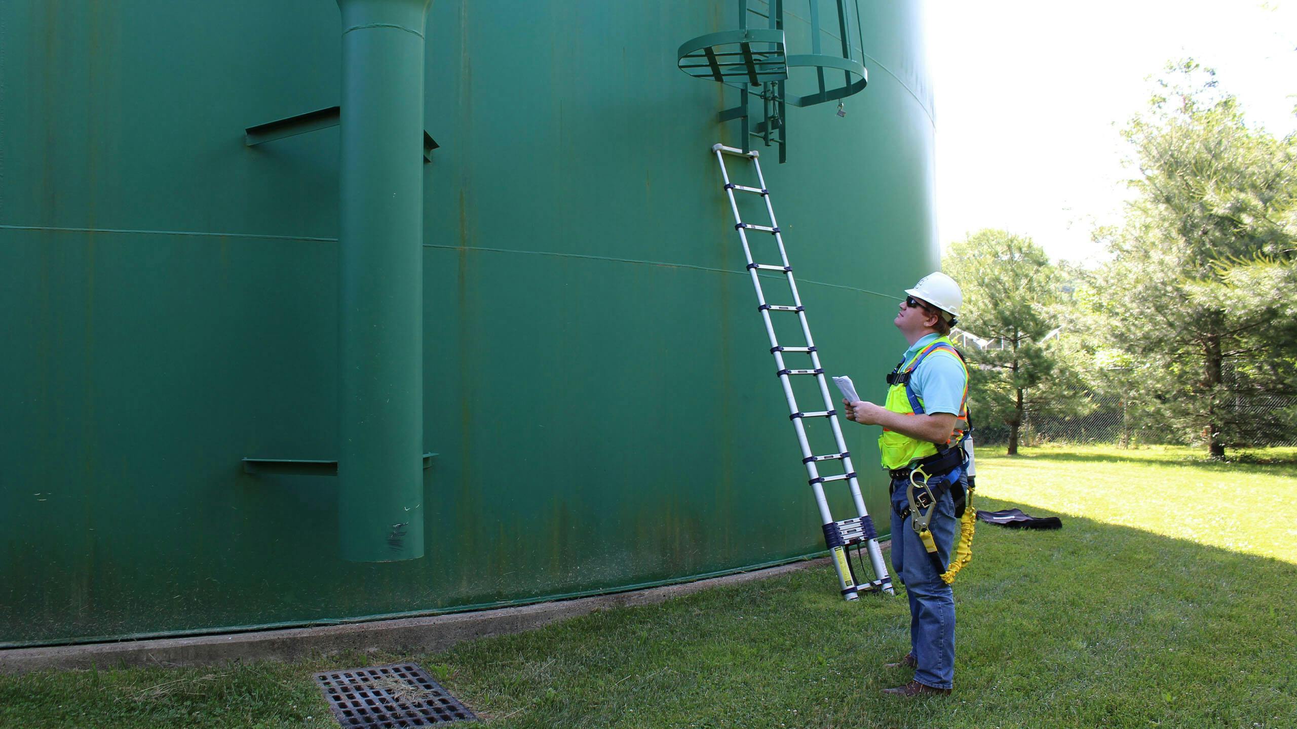 Man in PPE looking up at water tank
