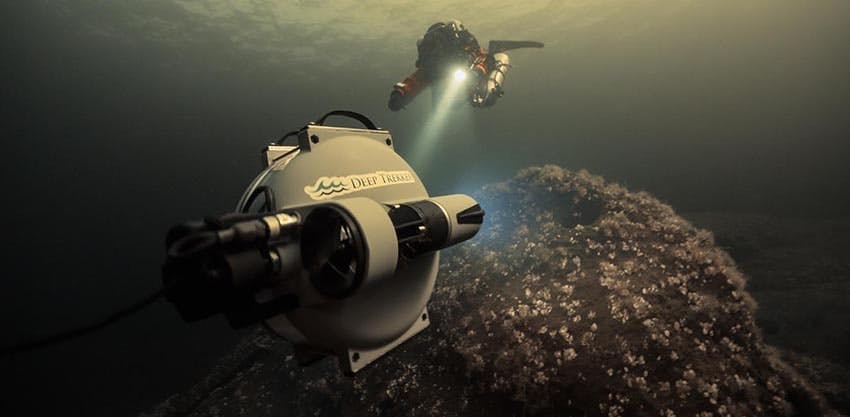 Scuba diver underwater pointing flashlight at a Deep Trekker DTG3 underwater ROV